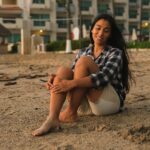 A woman sits on a sandy beach at sunset, embracing tranquility in Mexico.